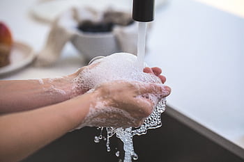Close-up of hands being washed with foamy soap under a faucet, highlighting hygiene and cleanliness. HD wallpaper