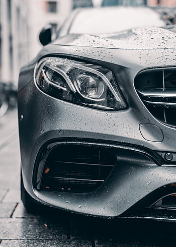 Close-up of a sleek luxury car with raindrops on a city street. HD phone wallpaper