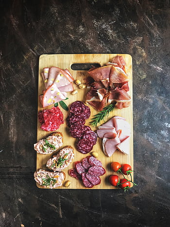 Delicious selection of cold cuts and bread on a wooden board with fresh herbs and tomatoes. HD phone wallpaper