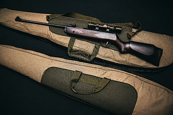 Close-up of a hunting rifle with a scope on a carrying bag, showcasing firearms and hunting gear. HD wallpaper