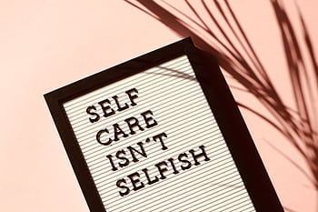 Letter board displaying 'Self Care Isn't Selfish' with artistic shadow on pink background. HD wallpaper