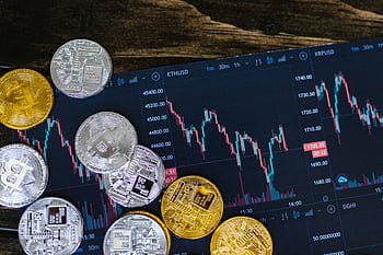 Close-up of gold and silver cryptocurrency coins on a digital trading chart. HD wallpaper