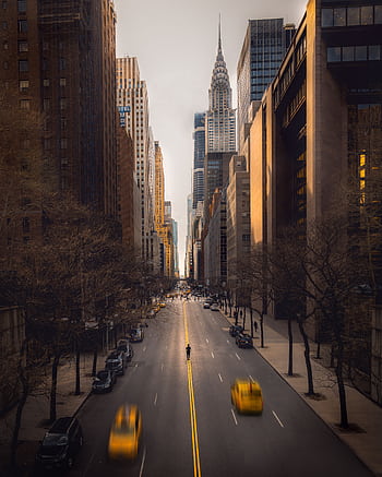 A bustling New York City street featuring yellow taxis, modern skyscrapers, and iconic architecture. HD phone wallpaper