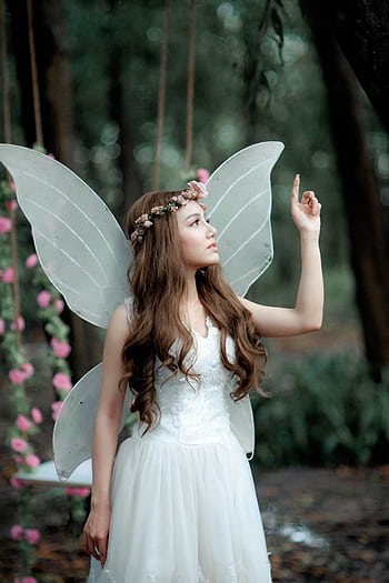 A beautiful woman in white fairy costume posing elegantly in a forest setting. HD phone wallpaper