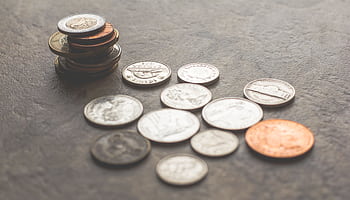 Assorted foreign coins stacked and scattered on a textured surface. HD wallpaper
