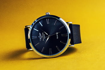 Stylish black analog wristwatch with a black strap on a vibrant yellow background. HD wallpaper