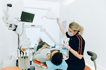 Female dentist examines patient's teeth in modern clinic setting. HD wallpaper