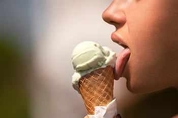 A close-up of a person enjoying a green ice cream cone on a sunny day. HD wallpaper