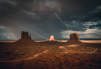 Stunning capture of a lightning storm illuminating Monument Valley's iconic rock formations. HD wallpaper