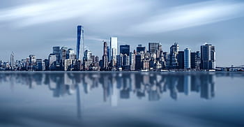 Stunning New York City skyline with modern skyscrapers reflecting on a calm river. HD wallpaper