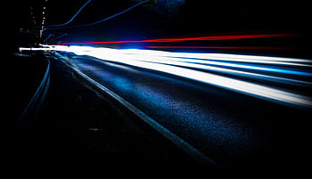 Long exposure shot of vibrant light trails on a highway at night, showing urban motion and speed. HD wallpaper