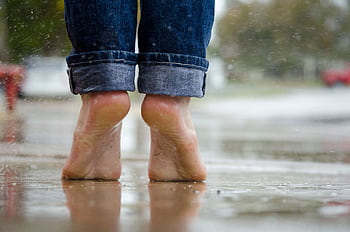 Close-up of bare feet on a wet pavement, capturing calm and connection with nature. HD wallpaper