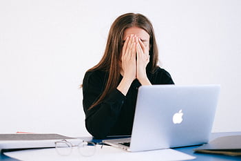 Woman feeling stressed and overwhelmed at her desk while working remotely on a laptop. HD wallpaper