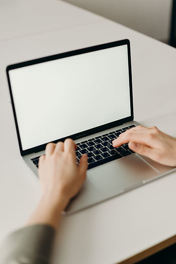 Close-up of hands typing on a laptop with a blank screen in a modern workspace. HD phone wallpaper