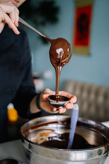 Close-up of chocolate ganache pouring into a container, showcasing culinary detail. HD phone wallpaper