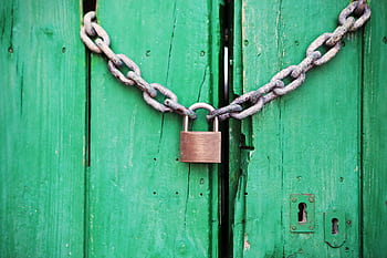 A rustic green wooden door secured with a heavy chain and padlock, symbolizing security. HD wallpaper