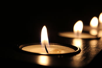 Close-up of glowing candle flames in the dark, creating a warm ambiance. HD wallpaper