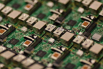 Detailed shot of a Raspberry Pi circuit board showcasing its components, USB ports, and microchips. HD wallpaper