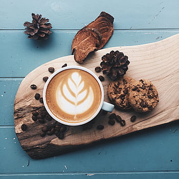 A cappuccino with latte art served with cookies on a rustic wooden board, perfect for coffee lovers. HD phone wallpaper