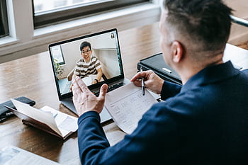 A professional having a video conference on a laptop from a home office, engaging in online communication. HD wallpaper