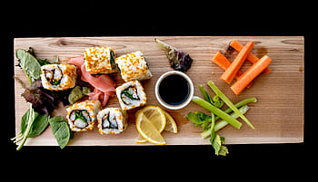 Top-down view of a sushi platter with fresh vegetables, perfect for a healthy meal. HD wallpaper
