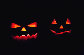Two illuminated jack-o'-lanterns in dark, creating an eerie Halloween atmosphere. HD wallpaper