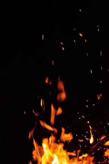 Close-up of bright flames and sparks in the dark night creating a warm ambiance. HD phone wallpaper