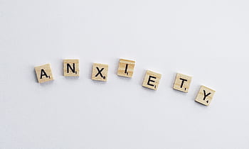 Wooden tiles on a white background spell anxiety, symbolizing mental health awareness. HD wallpaper