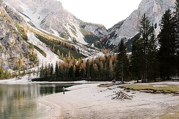 A serene mountain lake with snowy peaks and vibrant fall foliage under clear skies. HD wallpaper