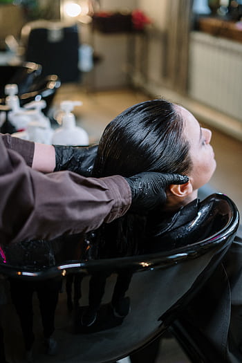 A professional hairstylist washing a woman's hair in a modern salon setting, ensuring quality haircare. HD phone wallpaper