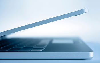 Profile view of a sleek modern laptop in a minimalist style, highlighting its slim design and technology focus. HD wallpaper