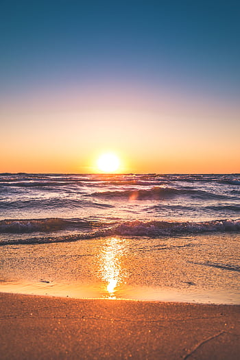 Experience the serene sunset over Ludington Beach with vibrant colors and tranquil waves. HD phone wallpaper