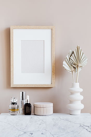 Elegant cosmetic setup with framed art and decor on a marble surface, perfect for modern interiors. HD phone wallpaper