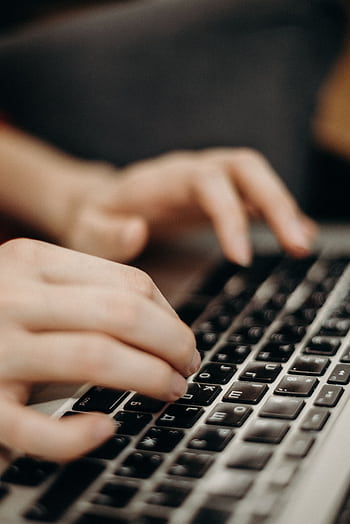 Close-up shot of hands typing on a laptop keyboard in a work environment. HD phone wallpaper