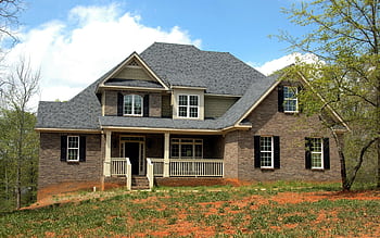 Classic two-story brick house with gable roof and front lawn in suburban setting. HD wallpaper
