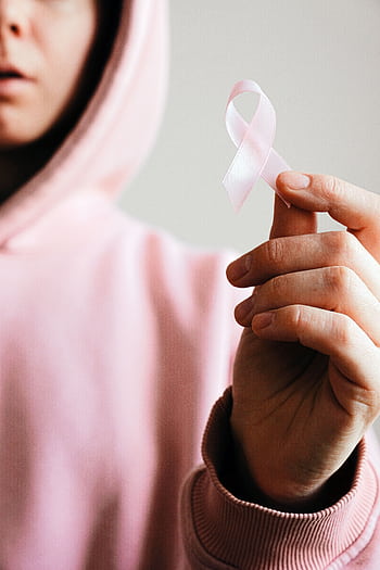 Close-up of a person holding a pink ribbon symbolizing breast cancer awareness. HD phone wallpaper