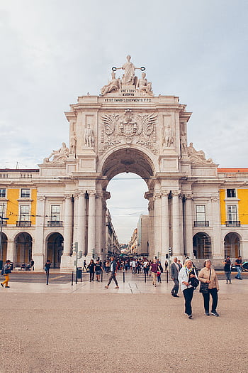 A scenic view of the iconic Rua Augusta Arch in Lisbon, Portugal with people strolling in the plaza. HD phone wallpaper