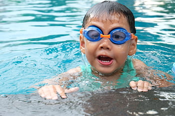 Young child playing and swimming in a pool, enjoying the water. HD wallpaper