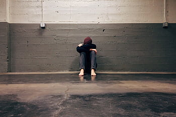 A person sitting alone in a corner, evoking themes of solitude and emotion. HD wallpaper