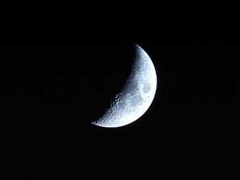 A detailed view of the crescent moon against a dark night sky, showcasing lunar craters. HD wallpaper