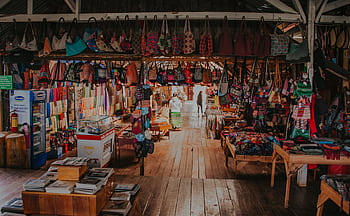 A colorful array of handcrafted bags and textiles in a lively indoor market setting. HD wallpaper