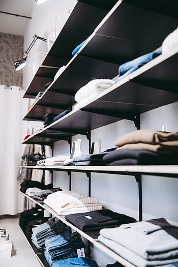 Neatly organized shelves with folded clothes in a contemporary store setting. HD phone wallpaper