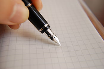 A detailed close-up of a fountain pen poised over graph paper, ideal for educational or business use. HD wallpaper