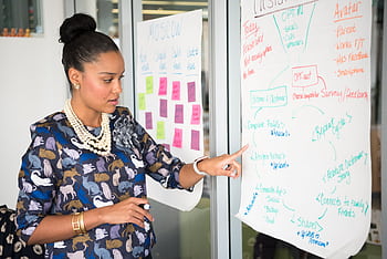 Professional woman presenting business strategy on paper in office. Engaged in workplace discussion. HD wallpaper
