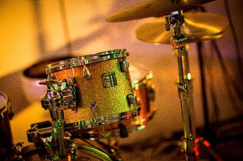 A vibrant close-up of a glittery drum set under concert lights, evoking a lively music performance. HD wallpaper