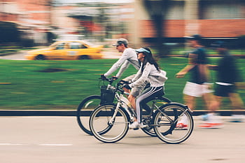Blurred of a couple cycling in a city street, capturing speed and motion. HD wallpaper