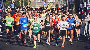 A large group of marathon runners competes outdoors in broad daylight, showcasing endurance and fitness. HD wallpaper