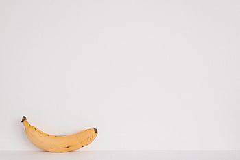 A single yellow banana against a clean white background. Perfect for minimalist designs. HD wallpaper