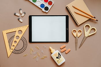 Flat lay of school supplies including tablet, scissors, glue, and stationery. Ideal for education themes. HD wallpaper