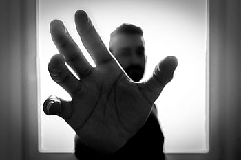 Black and white close-up of hand reaching out with blurred figure in background. HD wallpaper